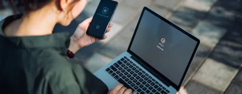Bizneswoman pracująca na zewnątrz, logująca się do laptopa i smartphona