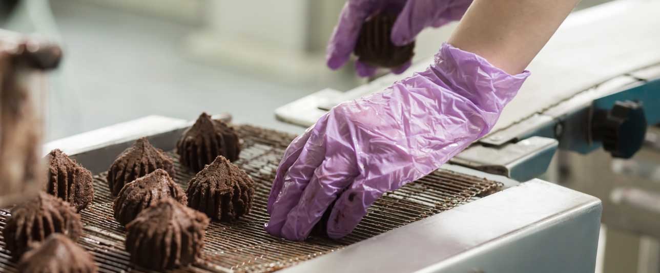 Ręka wkładająca słodycze na przenośnik